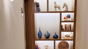 A hallway with a marble floor, a wooden bookshelf with decorative items, and a wall-mounted light fixture. - Dna Hotel Dalyan Adult Only (Ortaca)