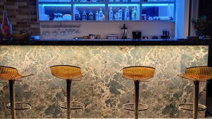 A bar area with a marble countertop, three bar stools, and shelves with bottles and glasses. - Dna Hotel Dalyan Adult Only (Ortaca)