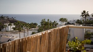 Una terrassa amb vistes al mar, palmeres i edificis.