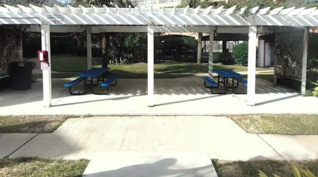 A covered outdoor seating area with tables and benches.