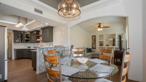 A spacious kitchen with dark cabinets, a central island, and a dining area with a glass table and wooden chairs. - Incredible home with custom pool and fountain (El Paso)