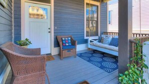 A porch with wicker chairs, a swing, and a door with a window.