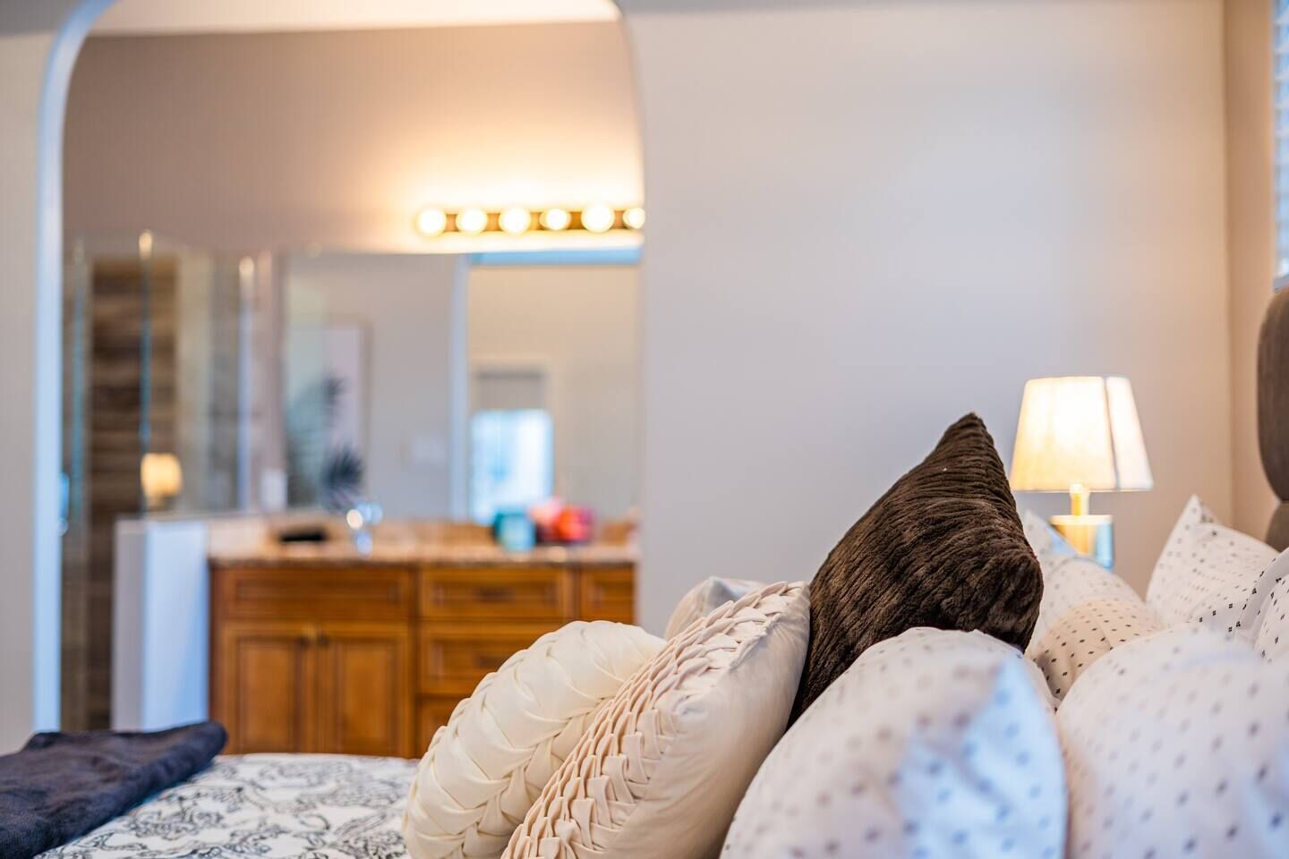 A bedroom with a bed, pillows, a nightstand, and a dresser.