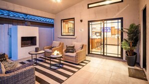 A cozy living area with wicker furniture, a fireplace, and a large sliding glass door leading to a kitchen. - The White House, Heated Pool! PuttingGreen (Phoenix)