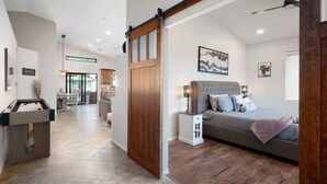 A modern bedroom with a large bed, wooden flooring, and a sliding barn door. - The White House, Heated Pool! PuttingGreen (Phoenix)