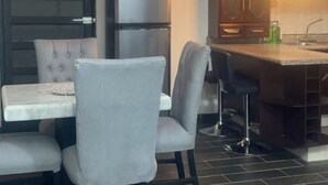 Een keuken met een koelkast met dubbele deuren, een marmeren aanrecht en barstoelen.