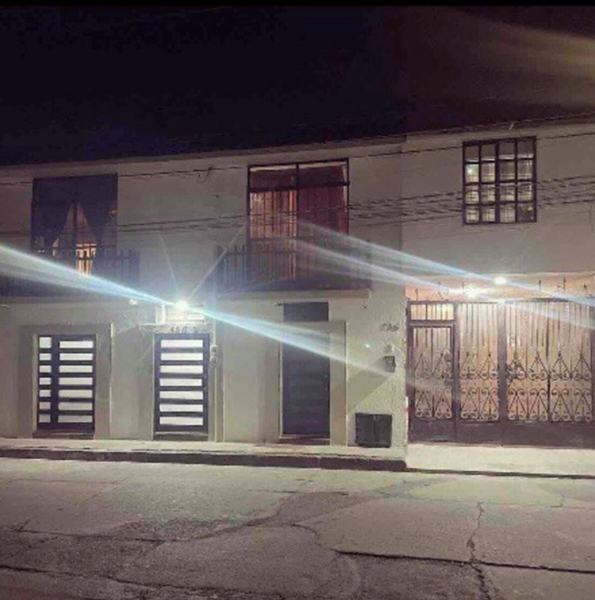 Un edificio con entrada protegida por una reja, un balcón y una puerta visible.