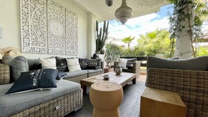 Una sala moderna con un sofá gris, muebles de mimbre y cojines decorativos.