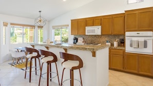 A modern kitchen with a large island, wooden cabinets, and a built-in microwave. - Golf Course Villa, Private Saltwater Pool & Spa (Indio)