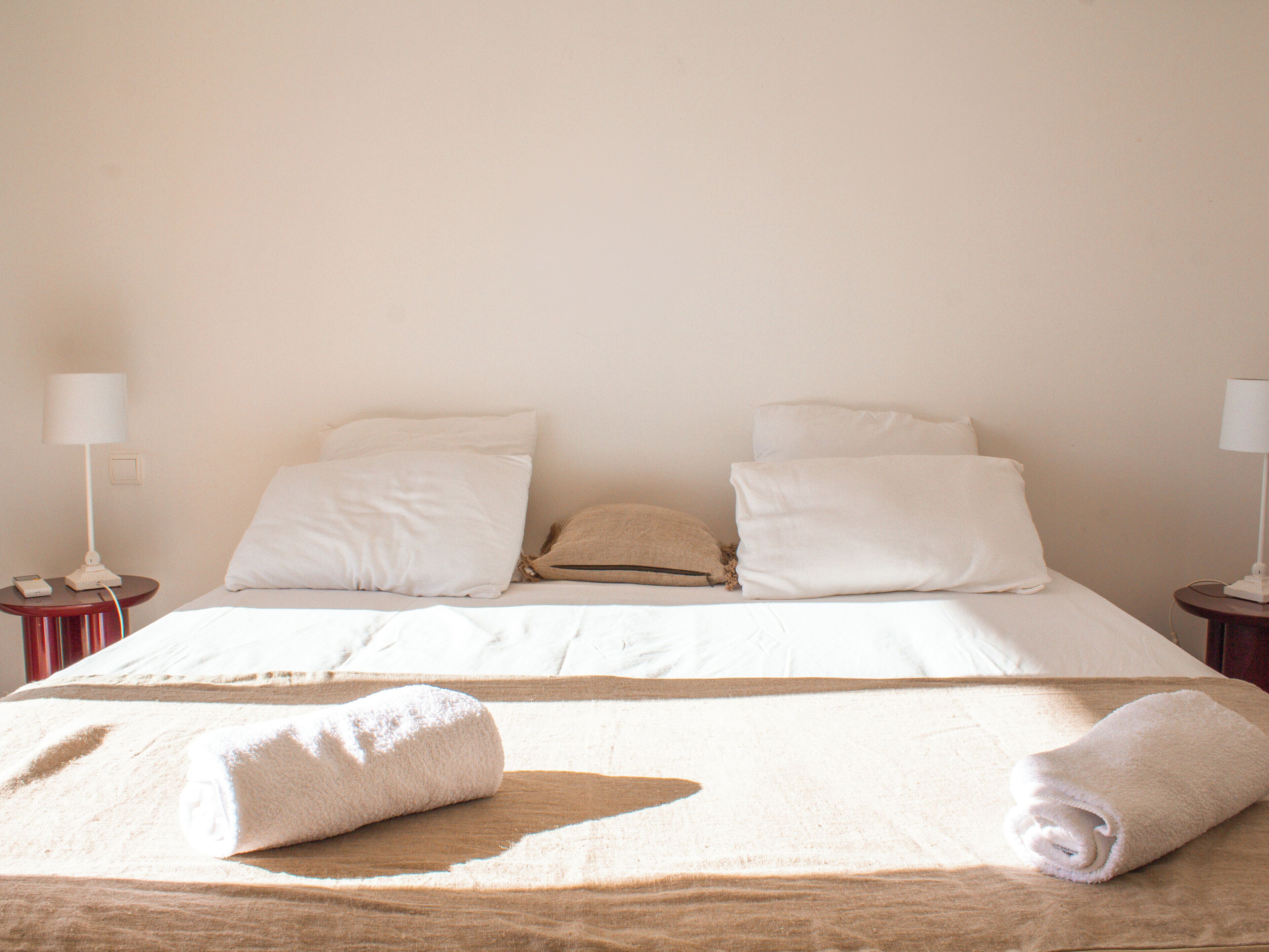 A hotel room with a bed, two bedside tables, and two lamps.