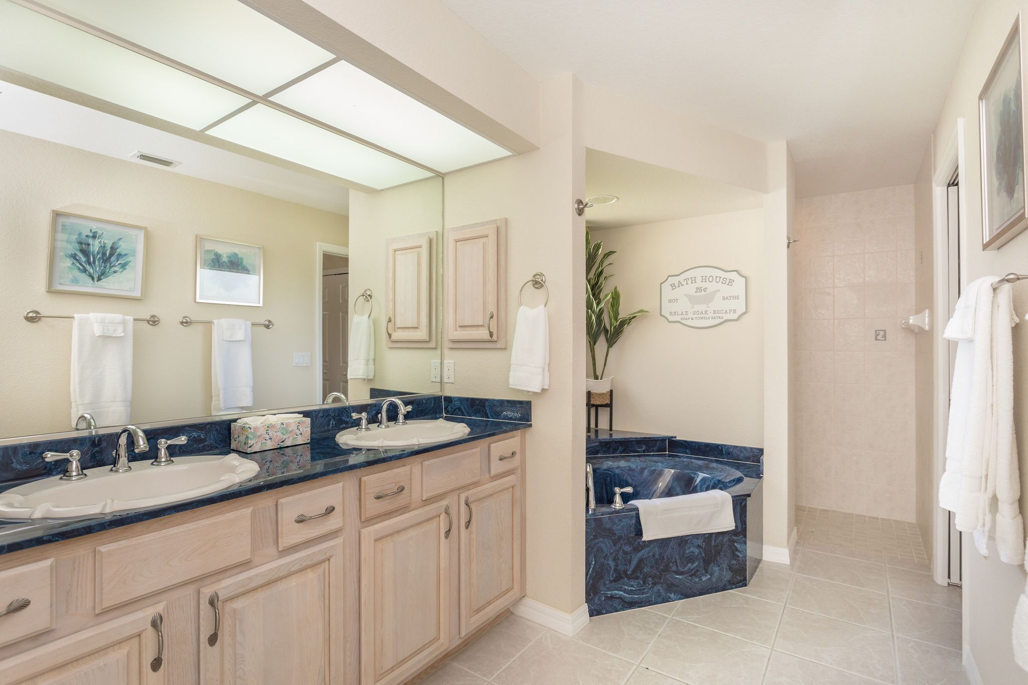 A modern bathroom with two sinks, a bathtub, and a large mirror.