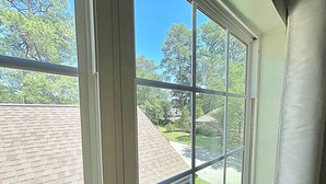 A view through a window with a brick wall and a clear blue sky. - Resort-Style Studio on the Golf Course! (Conroe)