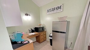 A compact kitchen with a refrigerator, microwave, and a 'Bless Our Home' sign. - Private Studio Retreat on the Golf Course (Conroe)
