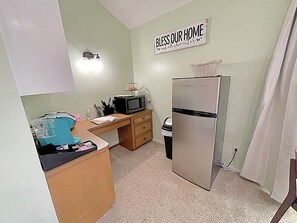 A compact kitchen with a refrigerator, microwave, and a 'Bless Our Home' sign. - Private Studio Retreat on the Golf Course (Conroe)