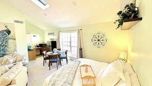 A bedroom with a bed, bedside table, and a small table with chairs in the adjacent dining area. - Private Studio Retreat on the Golf Course (Conroe)