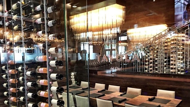 A wine cellar with racks of wine bottles, a dining area with tables and chairs, and a staircase leading to a higher level. - Resort-Style Studio on the Golf Course! (Conroe)