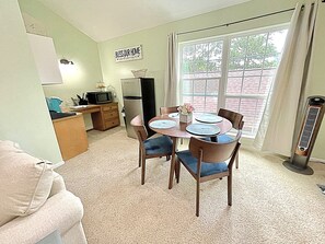 A compact living space with a dining area, kitchenette, and a view through a large window. - Private Studio on the Golf Course near The Woodlands (Conroe)