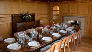 A dining room with a long wooden table set for a meal, flanked by wooden paneling and a fireplace. - Luxury Farmhouse:Padel court/Hot tub/pool table/fire pit. Central meet up point. (SELBY)