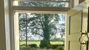 An open door leading to a stone pathway surrounded by greenery. - Luxury Farmhouse:Padel court/Hot tub/pool table/fire pit. Central meet up point. (SELBY)