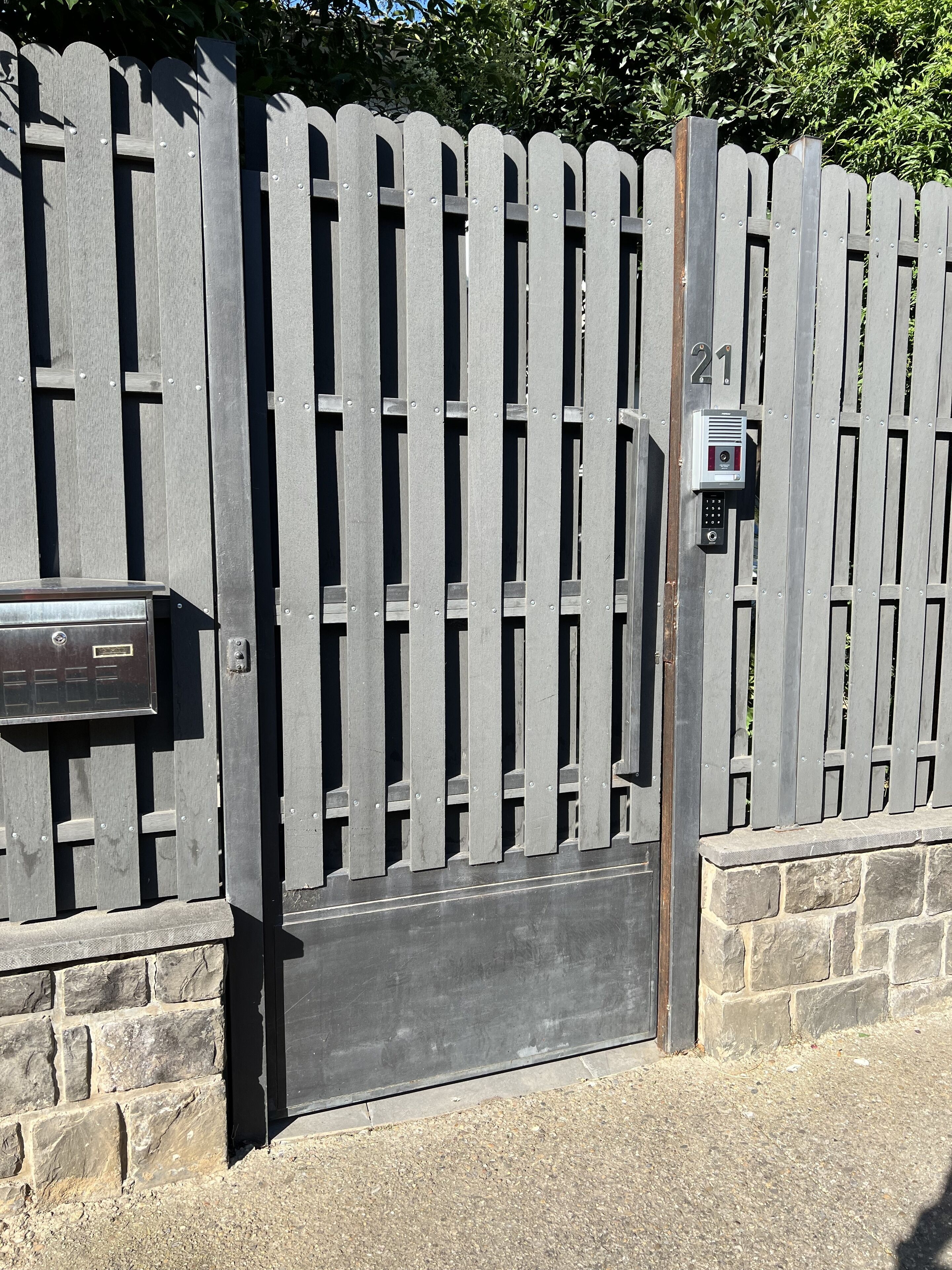 A metal gate with a keypad lock and a mailbox.