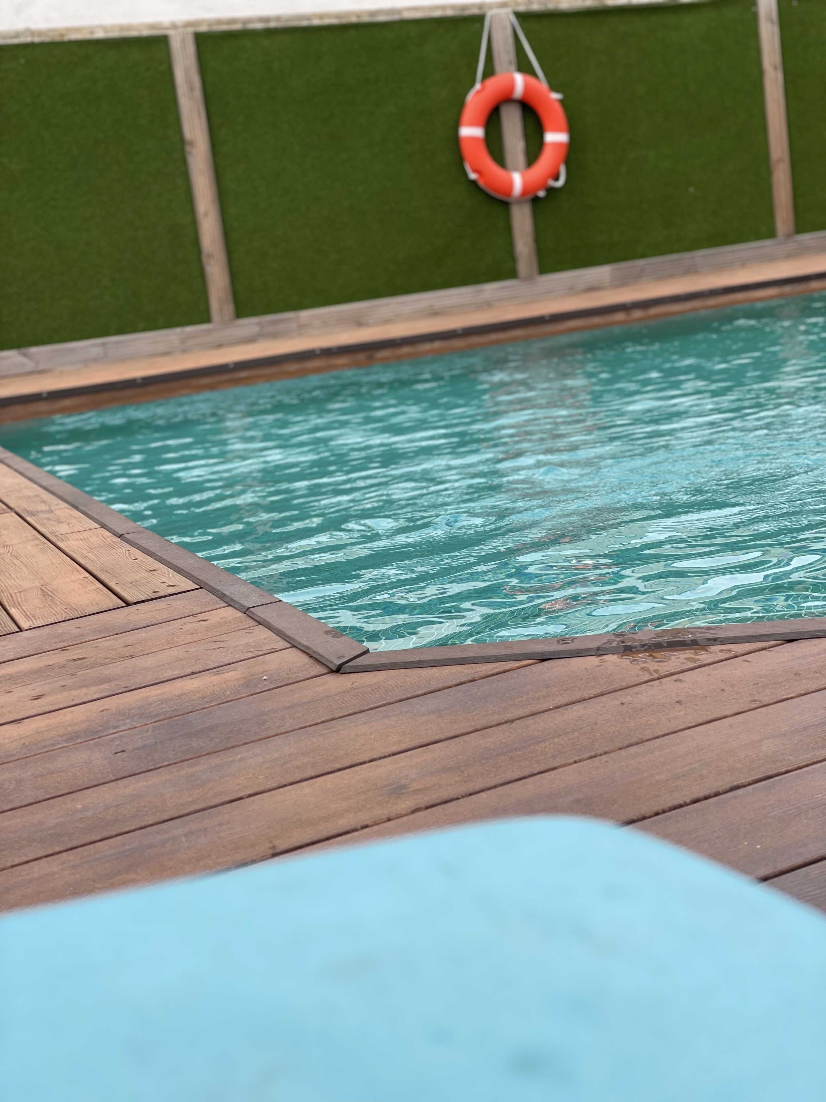 Una piscina con cubierta de madera y un flotador en la pared.