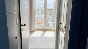 Ein Flur, der zu einem Balkon mit Blick auf einen Jachthafen und Gebäude führt.