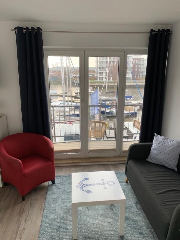 A room with a red armchair, a grey sofa, and a white coffee table.