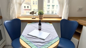 Ein kleiner Essbereich mit einem Tisch für zwei Personen, einem Laptop, einer Flasche und einem Blumentopf.