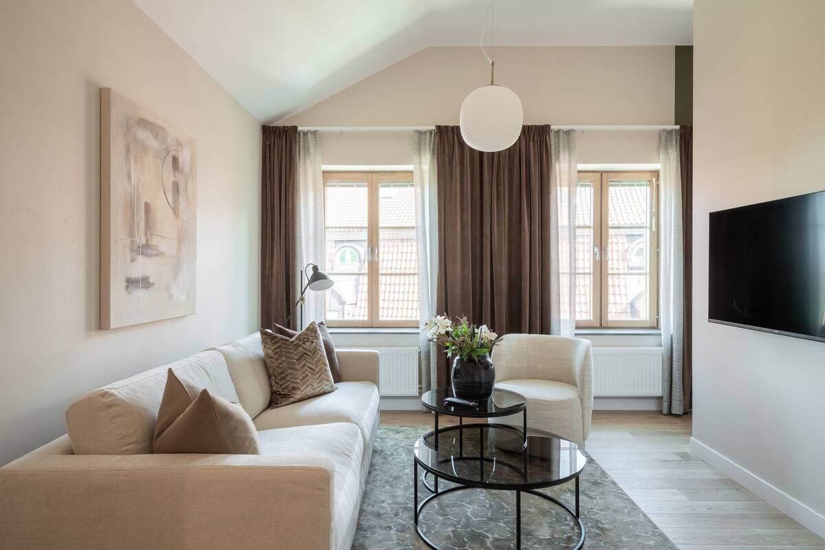Un salon moderne comprenant un canapé, un fauteuil, une table basse et un téléviseur à écran plat.