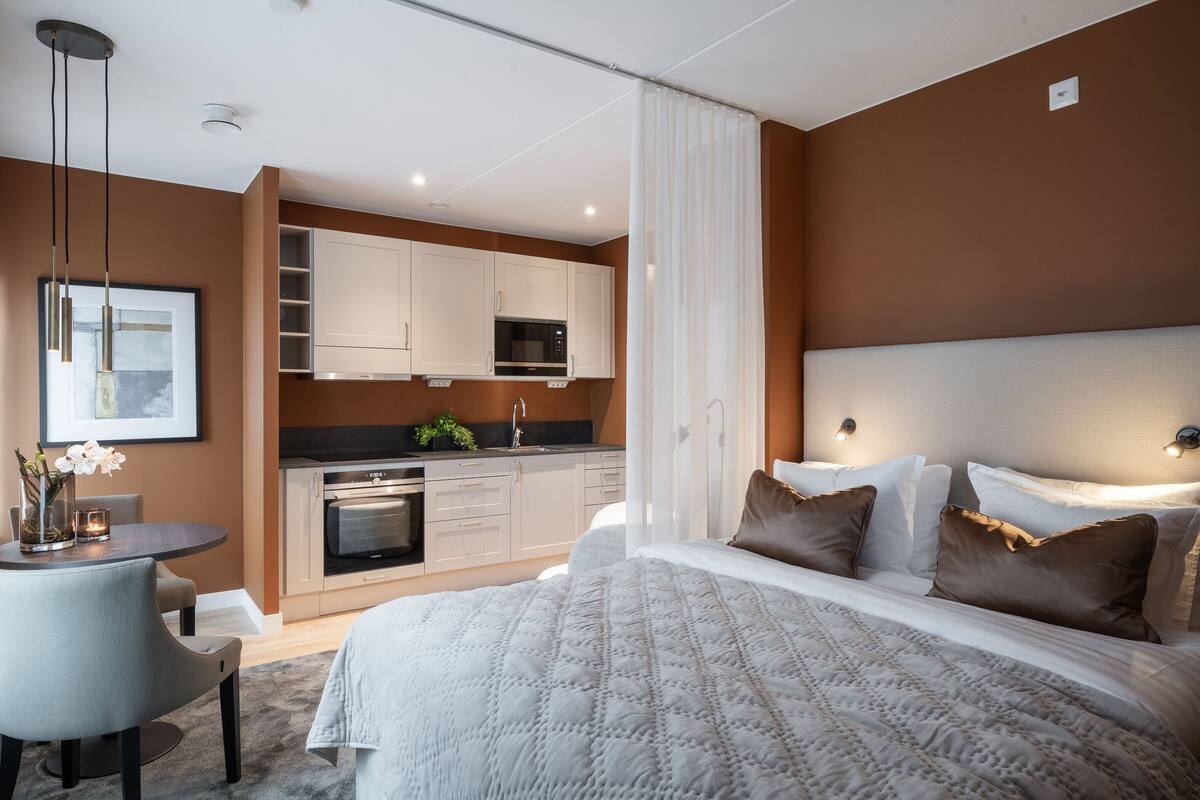 Une chambre d’hôtel moderne équipée d’un lit, d’une table de chevet et d’une kitchenette.