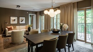 A modern dining area with a large table, chairs, and a chandelier. There is a sofa and a coffee table with decorative items. - Live and Stay - Ekmanska (Gothenburg)