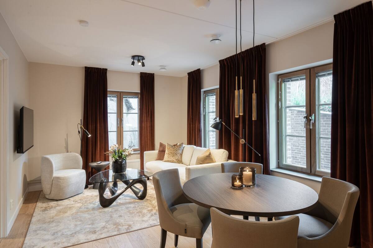 Un salon moderne avec un canapé, des fauteuils, une table basse et un téléviseur fixé au mur.