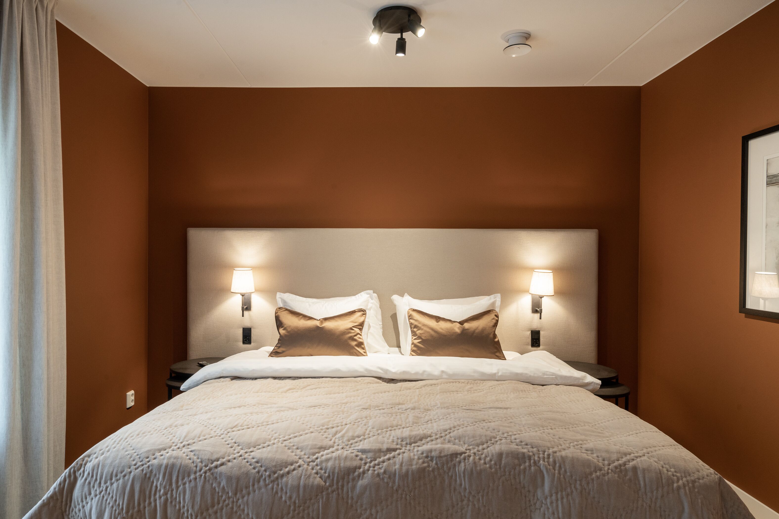 Ett hotellrum med en stor säng, två sänglampor och en taklampa.