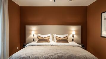 Ett hotellrum med en stor säng, två sänglampor och en taklampa.