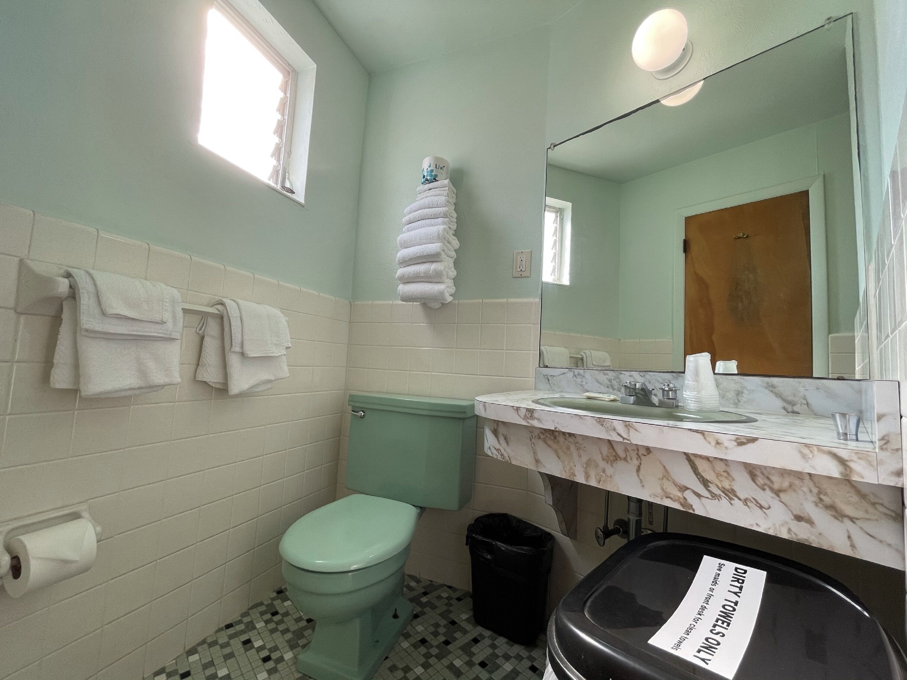 Un baño con inodoro, lavamanos y toallas apiladas.