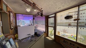 A room with a desk, computer, and a view of the street through large windows. - Bel Air Motel (Wildwood Crest)
