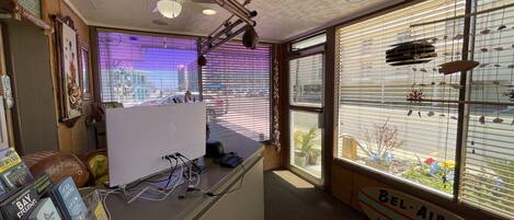 A room with a desk, computer, and a view of the street through large windows.