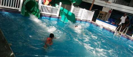 Una piscina con tobogán y socorrista.