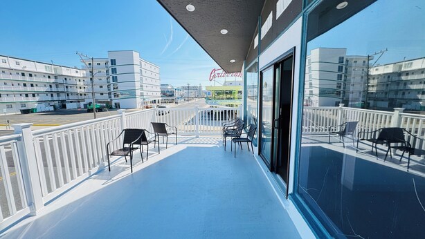 A balcony with chairs, a view of the street, and buildings in the background. - Bel Air Motel (Wildwood Crest)