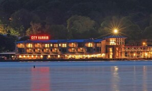 A waterfront hotel with a prominent 'CITY HARBOR' sign, multiple balconies, and a large illuminated structure to the right.