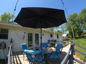 Eine Terrasse mit Gartenmöbeln, einem Grill und einem überdachten Bereich mit Sonnenschirm.