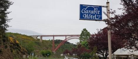 A sign for Garabit Hotel with a red bridge in the background.