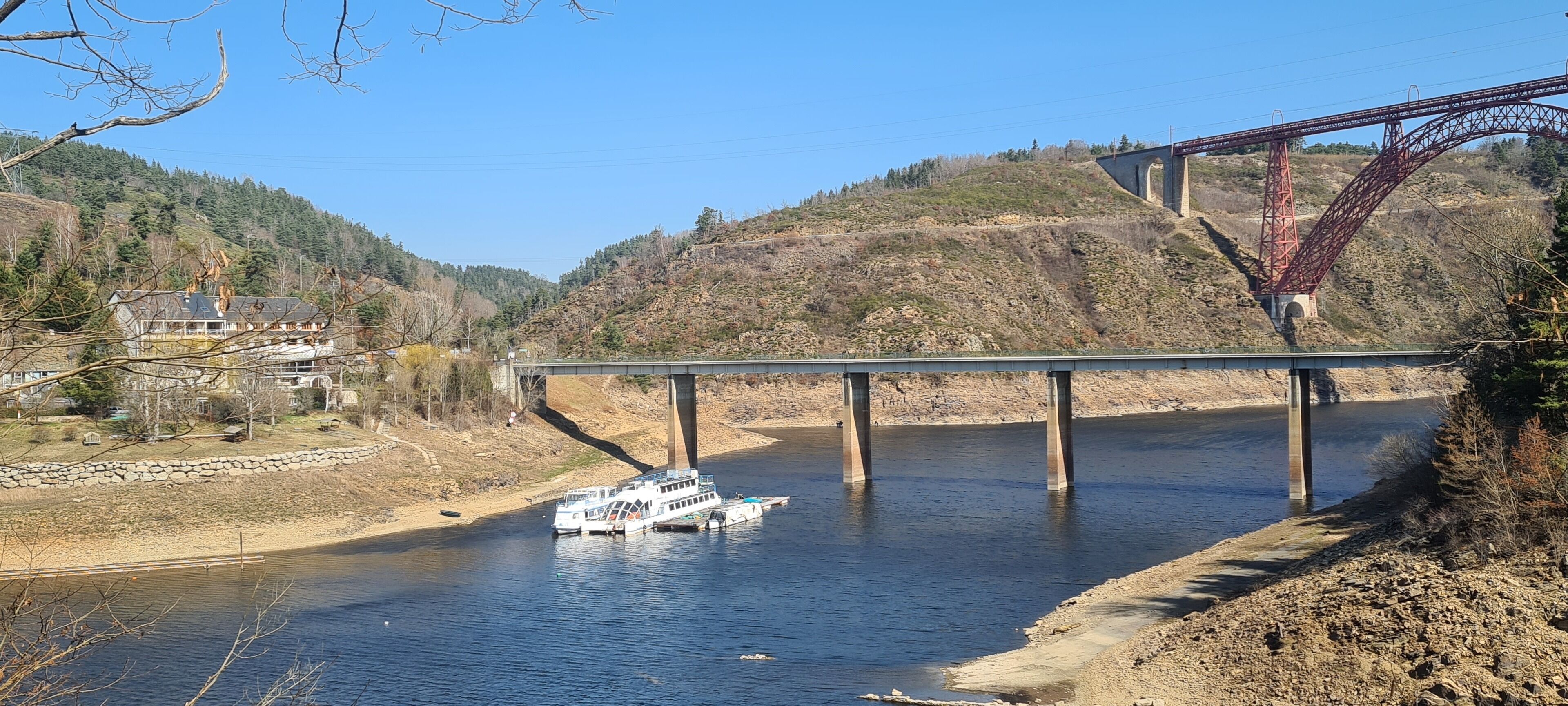 A river with a boat docked at a bridge.