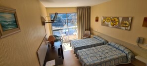 A hotel room with two beds, a desk with a lamp, a laptop, a painting, and a view of the outdoors. - Garabit Hôtel (Anglards-de-Saint-Flour)