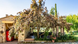 A stone building with a covered outdoor seating area and a tree in front. - For groups, in the heart of Tuscany 40 km from Pisa airport (Chianni)