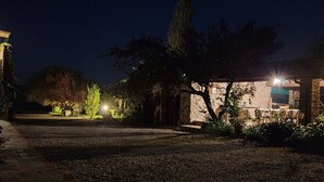 A nighttime view of a courtyard with a pathway leading to a building with a lit entrance. - For groups, in the heart of Tuscany 40 km from Pisa airport (Chianni)