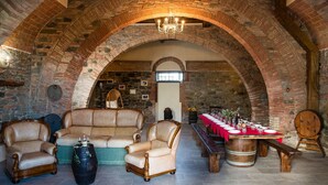 A rustic interior with stone arches, leather armchairs, a wooden table set for dining, and a barrel. - For groups, in the heart of Tuscany 40 km from Pisa airport (Chianni)