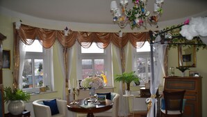 A room with a round table, two chairs, a potted plant, and a chandelier. - Vacation apartment "Fritz" in the Villa Hünlich with a rondel view of Upper Lusatia (Wilthen)