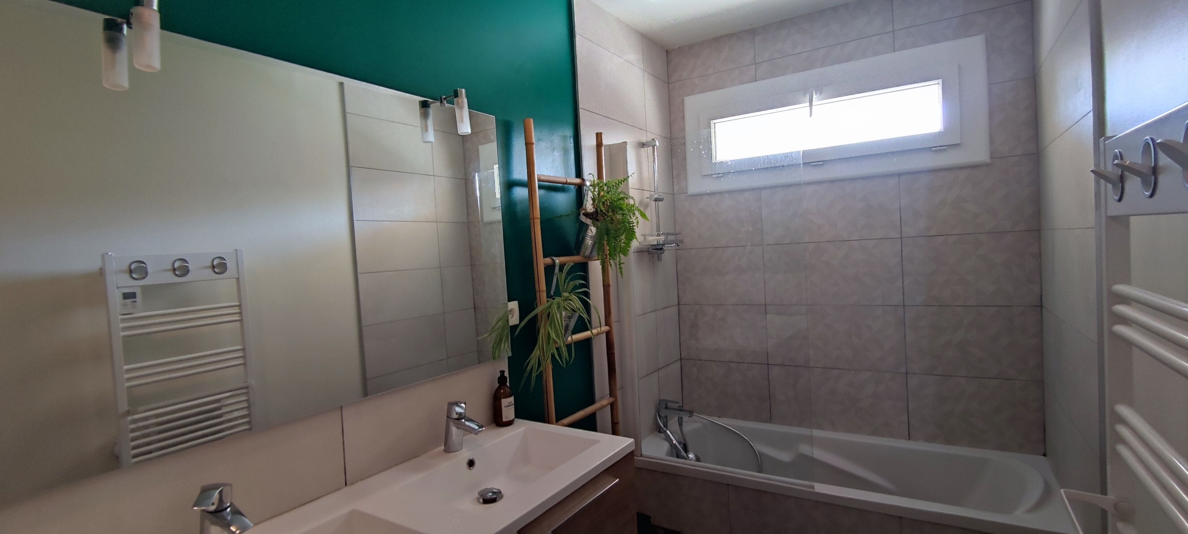Ein Badezimmer mit Waschbecken, Spiegel, Dusche und Fenster.