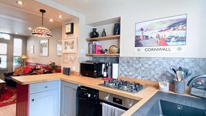A modern kitchen with a central island, built-in appliances, and a view of Cornwall. - The Old Bookshop - cheerful house located in St Ives centre (St Ives)